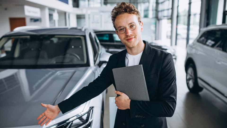 Ein Verkäufer zeigt auf ein Auto und erklärt dem Kunden die Konditionen beim Auto verkaufen Halle (Saale)